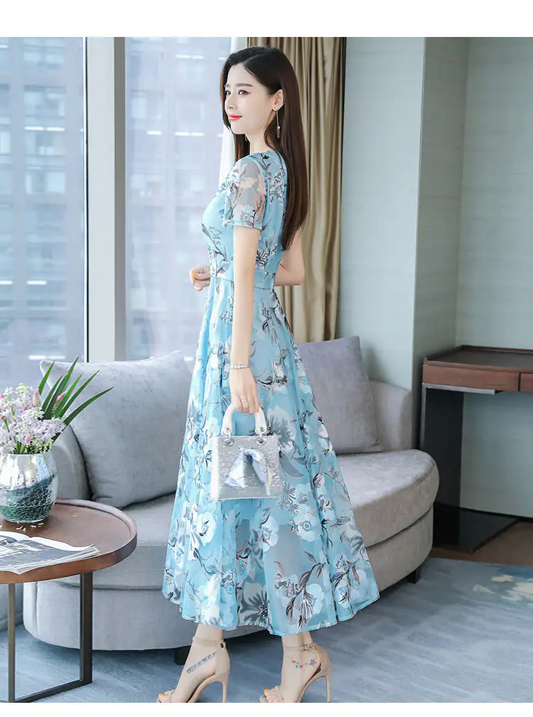 Woman in a light blue floral dress standing in a modern living room.