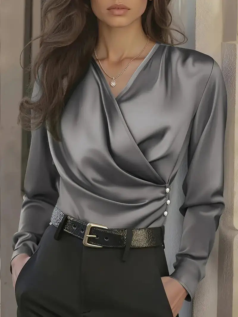 Woman wearing a gray satin blouse with a belt, standing against a neutral background.