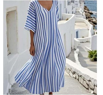 Person wearing a blue and white striped dress standing on a scenic coastal path.