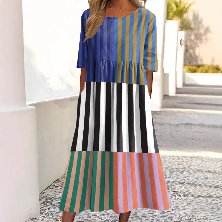 Woman wearing a colorful striped dress standing outdoors.